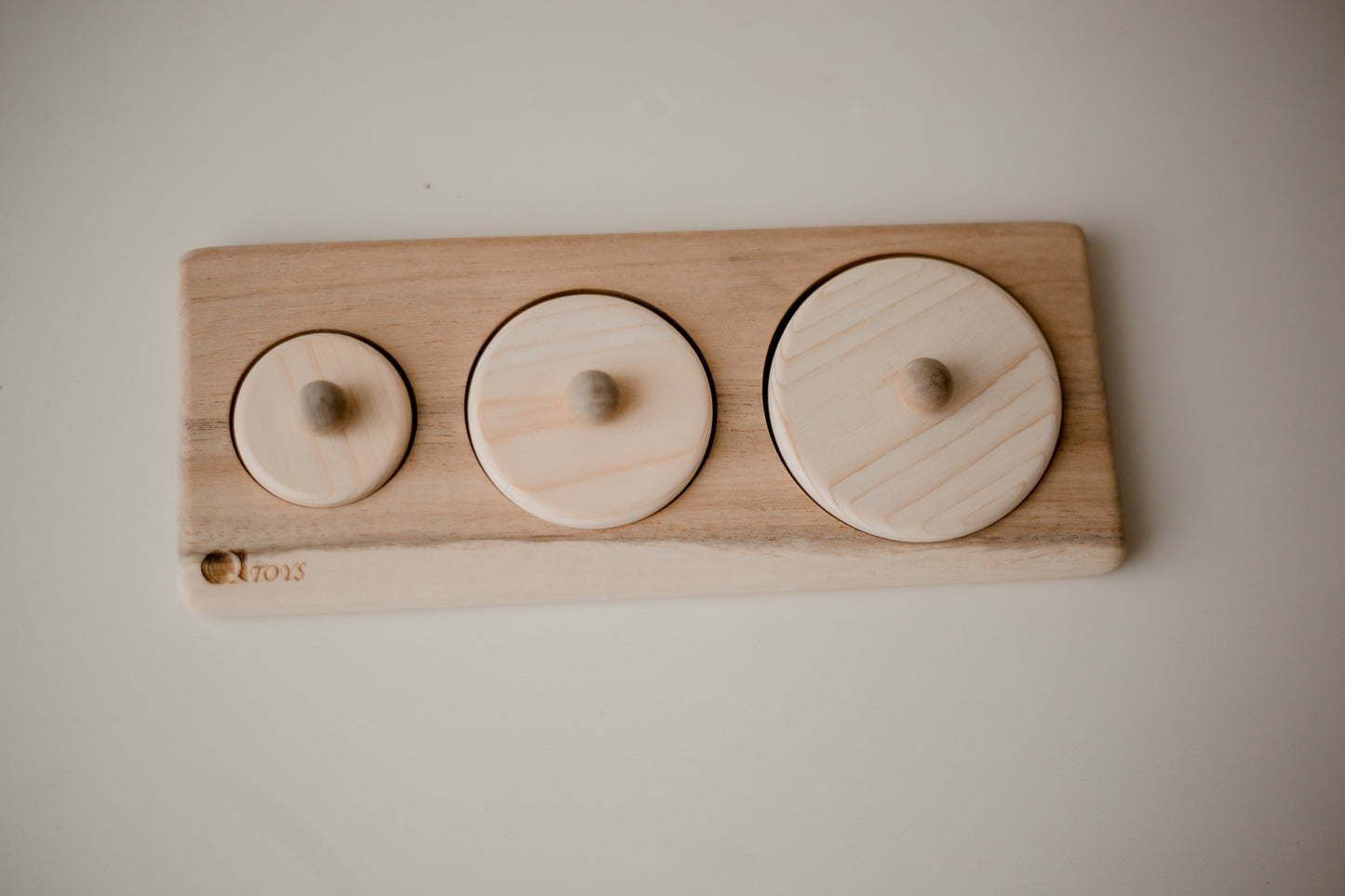 wooden puzzle consisting of 3 ascending circles. each puzzle has a small knob for child to hold.