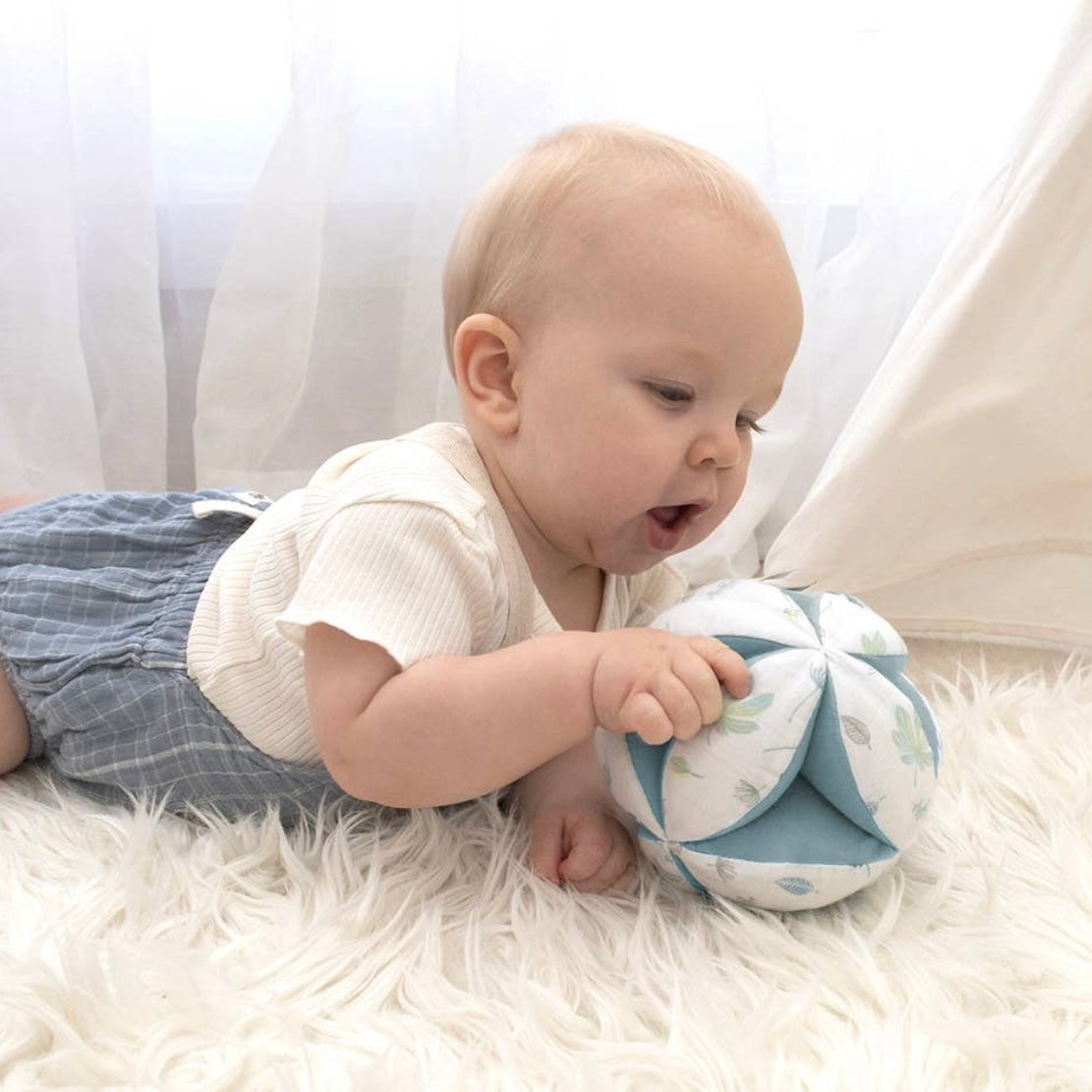 little boy playing with a soft ball during tummy time. 
