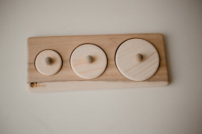 wooden puzzle consisting of 3 ascending circles. each puzzle has a small knob for child to hold. 